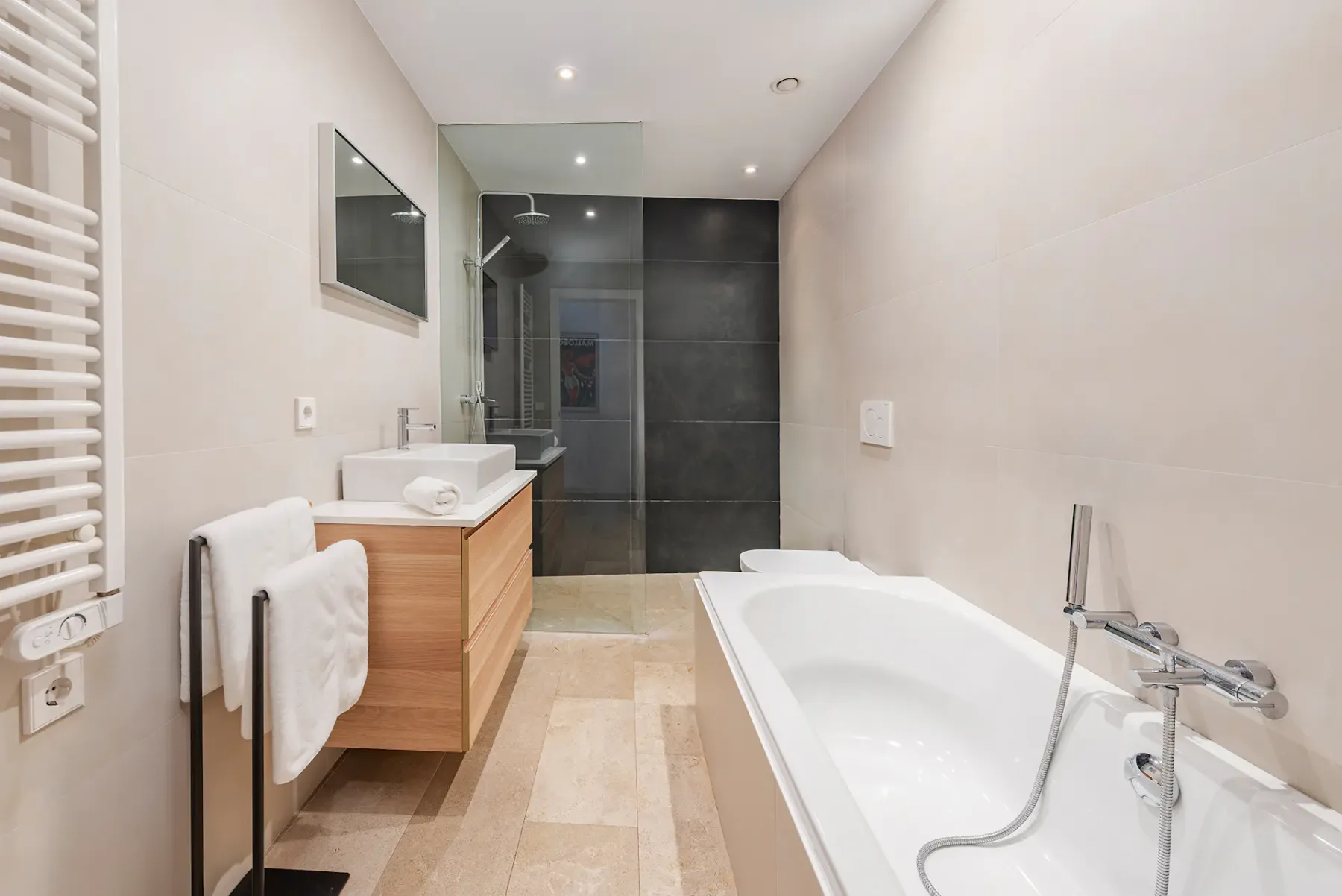 A bright bathroom with a bathtub, vanity, and glass shower.