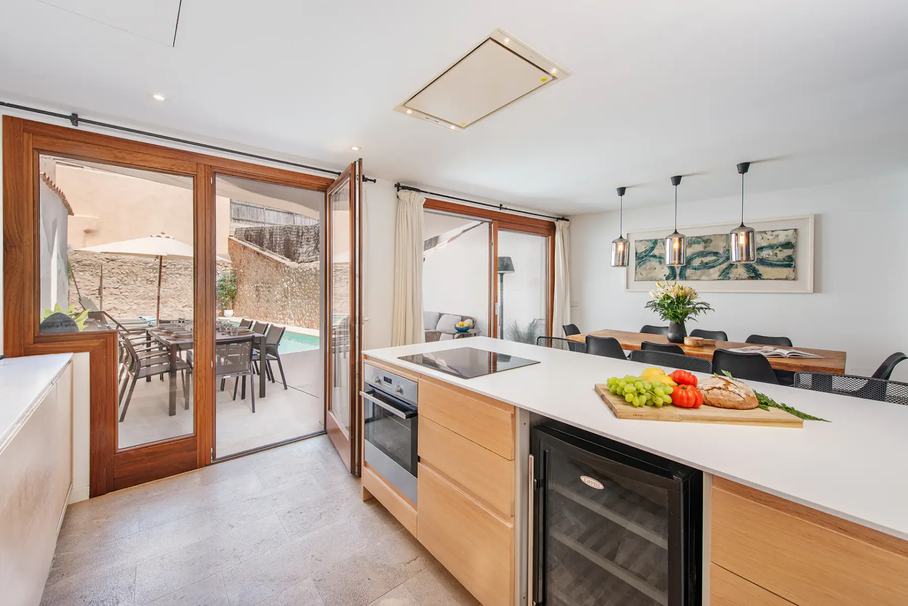 A modern kitchen opens onto a dining area and a patio.