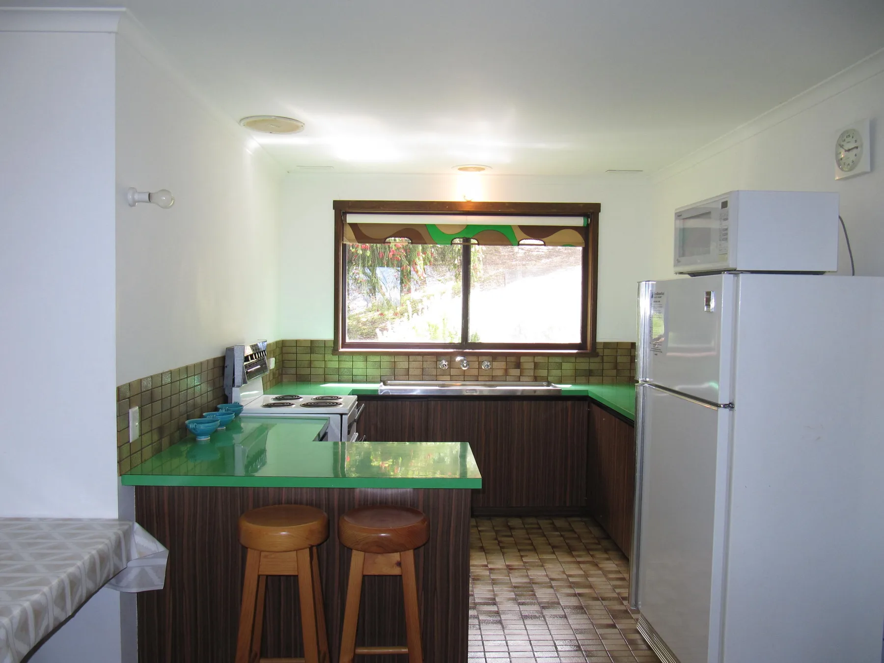 A kitchen with green countertops, a window, and a refrigerator.