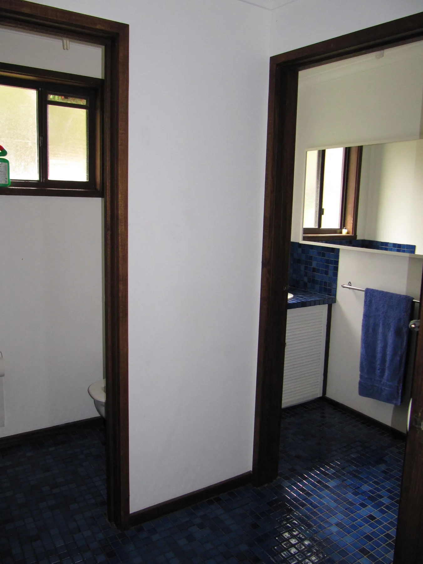 A bathroom with a blue tiled floor and a towel hanging beside the sink.