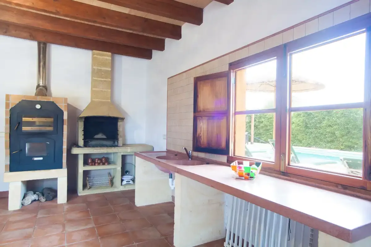 A rustic kitchen area with a built-in oven, fireplace, and large windows.