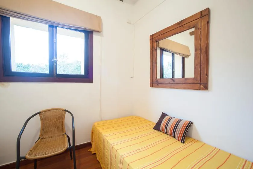 A bedroom with a single bed, striped bedding, and a window.