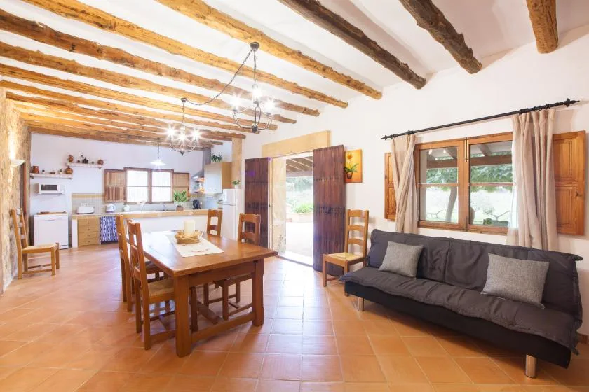 A dining and living area with a wooden table, seating, and an open kitchen.