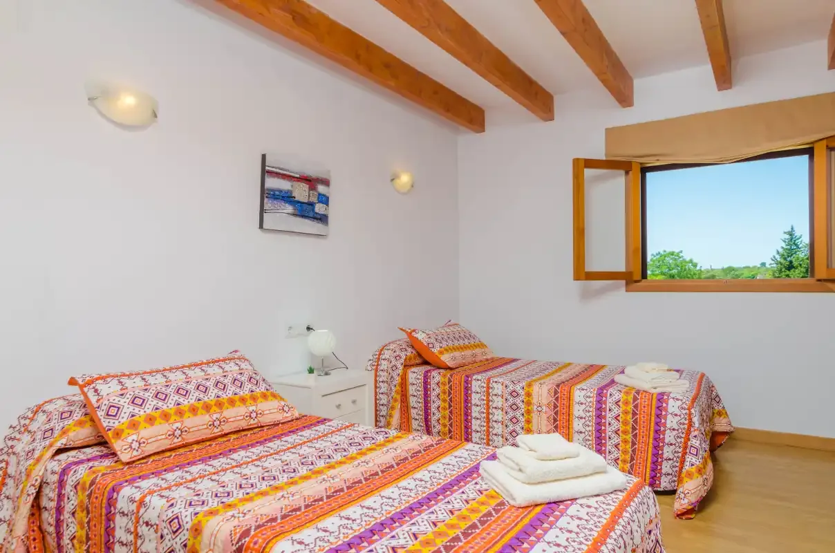 A bedroom with colorful patterned bedding and an open window.
