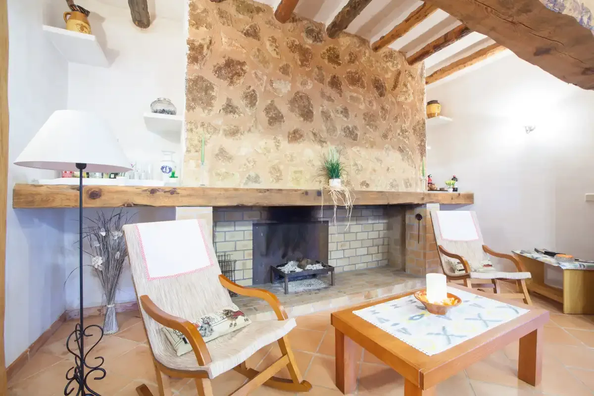 A rustic living room with a stone fireplace and wooden seating.