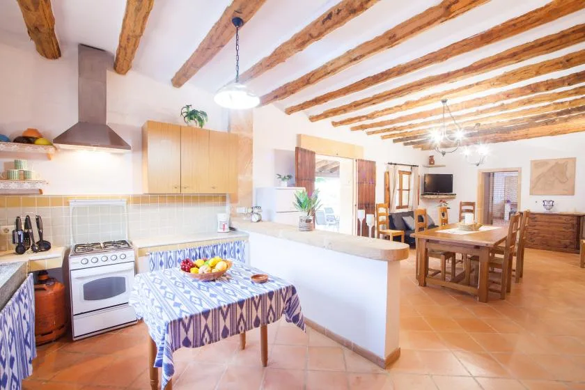 A bright kitchen and dining area with a table set beneath exposed wooden beams.