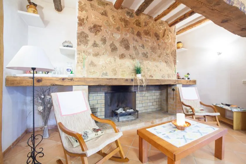 A rustic living room centers on a large stone fireplace and seating area.