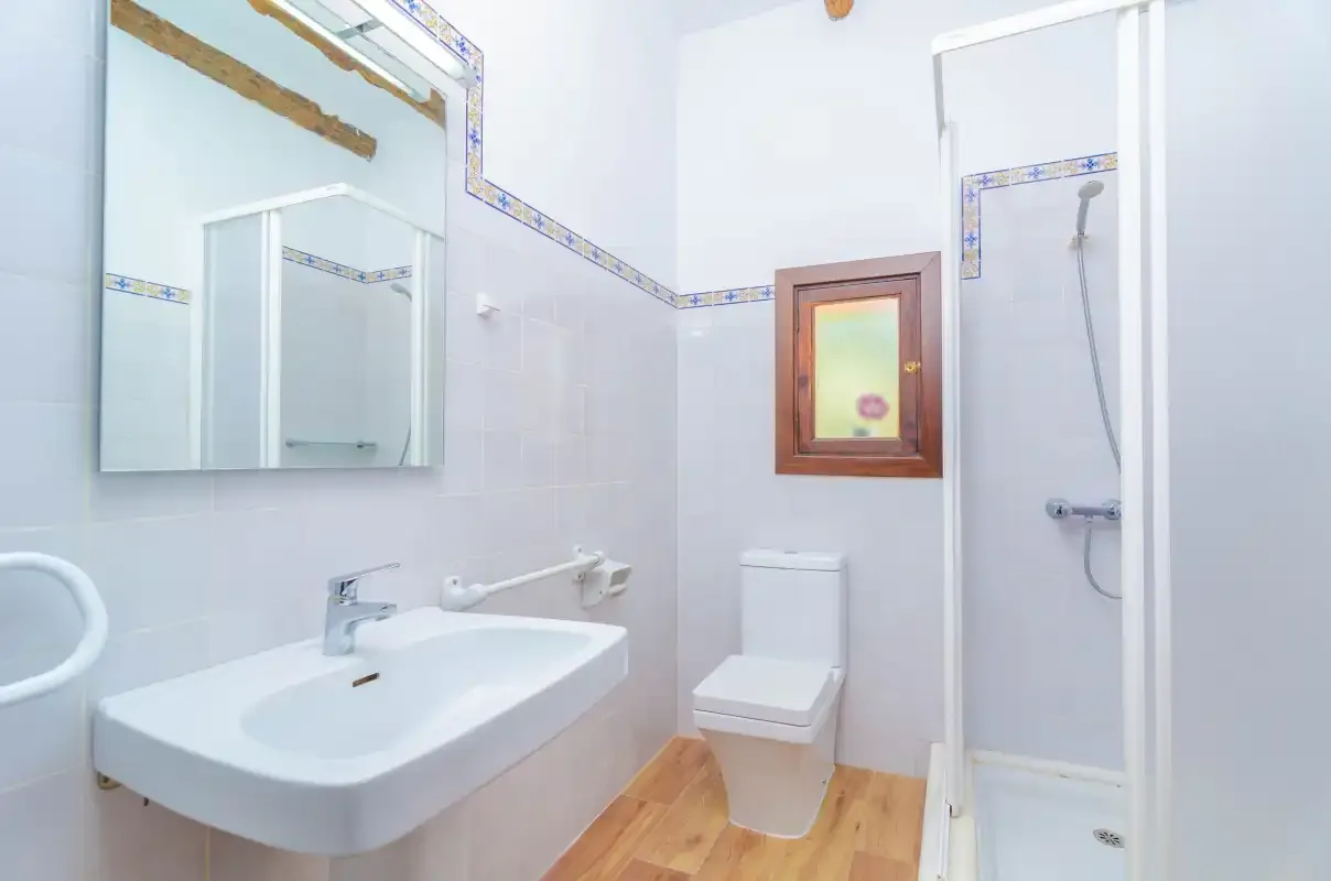 A bright bathroom with a sink, toilet, and shower.