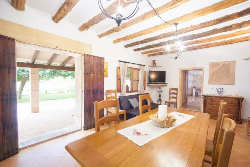 A dining room with a wooden table and exposed ceiling beams.