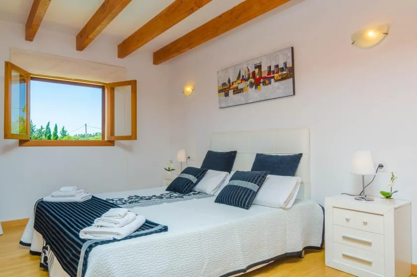 A bright bedroom with a double bed and an open window.