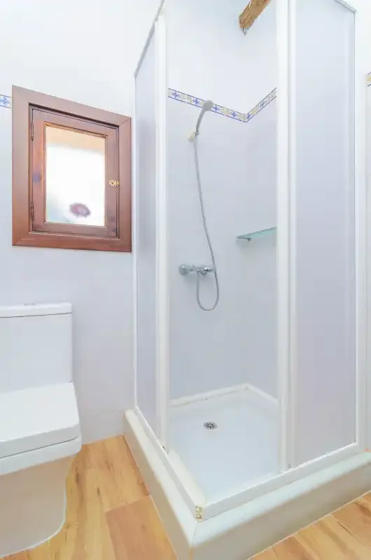 A bathroom with a glass-enclosed shower and a small window.