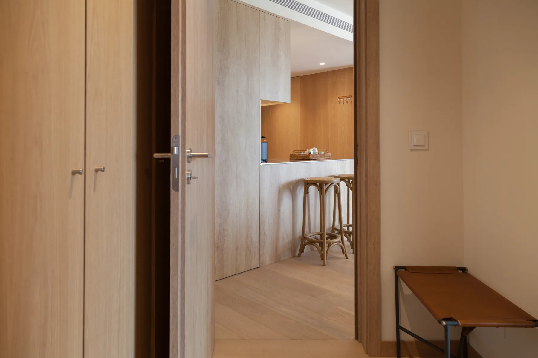 A doorway opens onto a kitchen with a counter and stools.