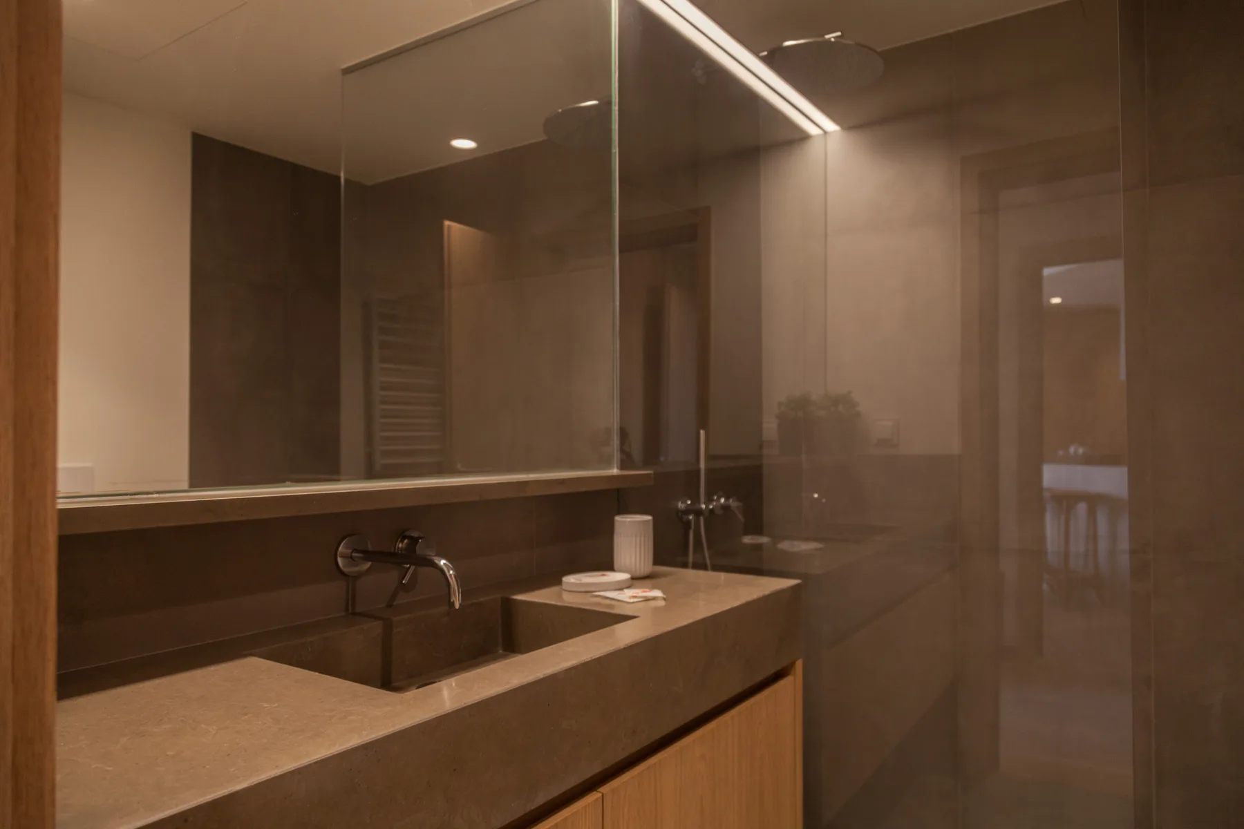 A bathroom vanity with a wide mirror and a wall-mounted faucet.