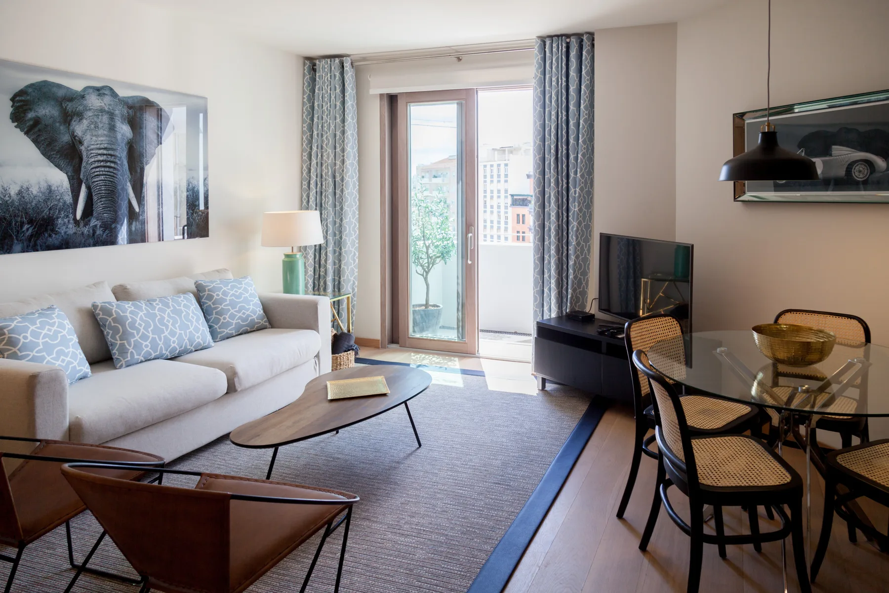 Sala de estar con asientos, un televisor y una mesa de comedor junto a la ventana.