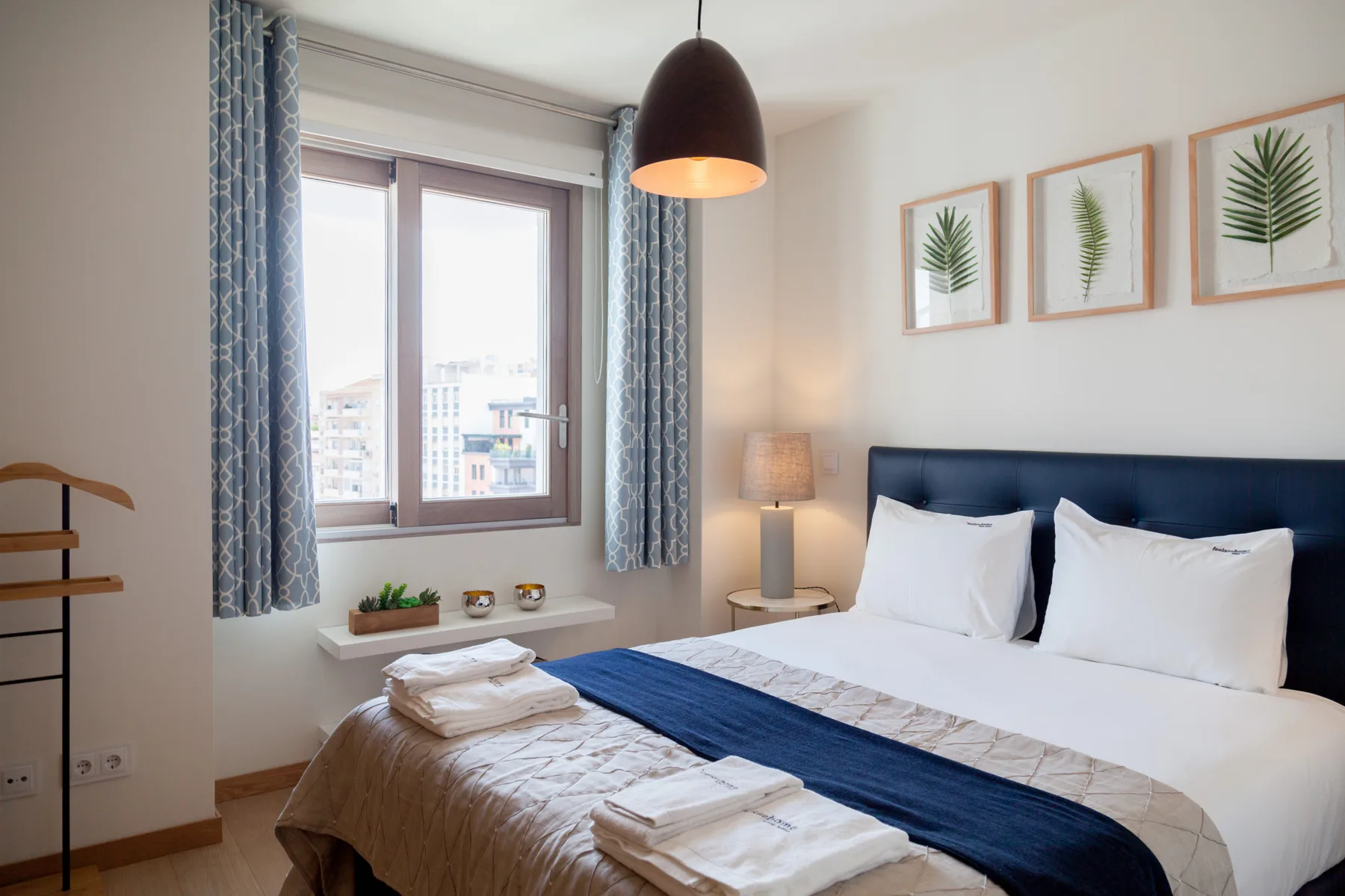 A bedroom with a neatly made bed and a large window.