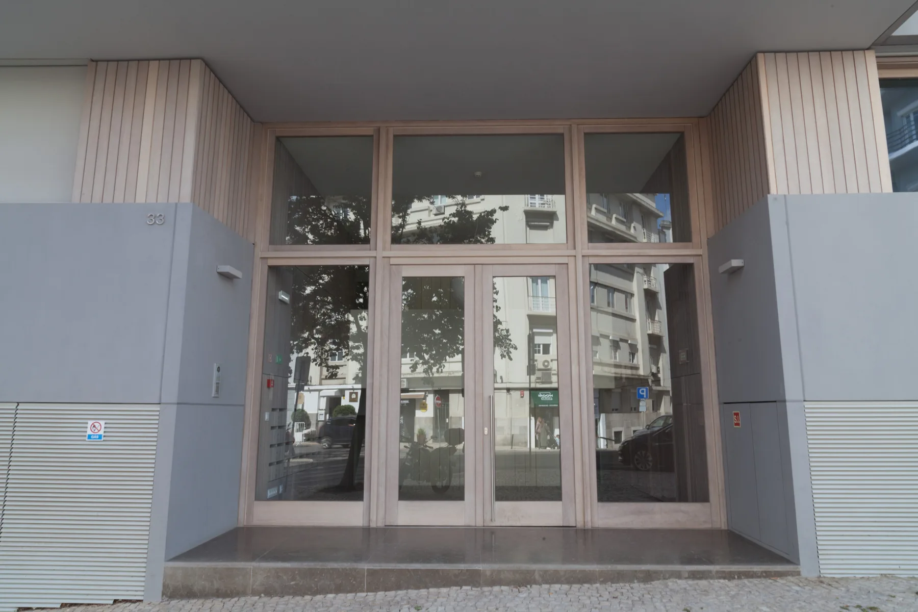 A glass-fronted building entrance opens onto a paved sidewalk.