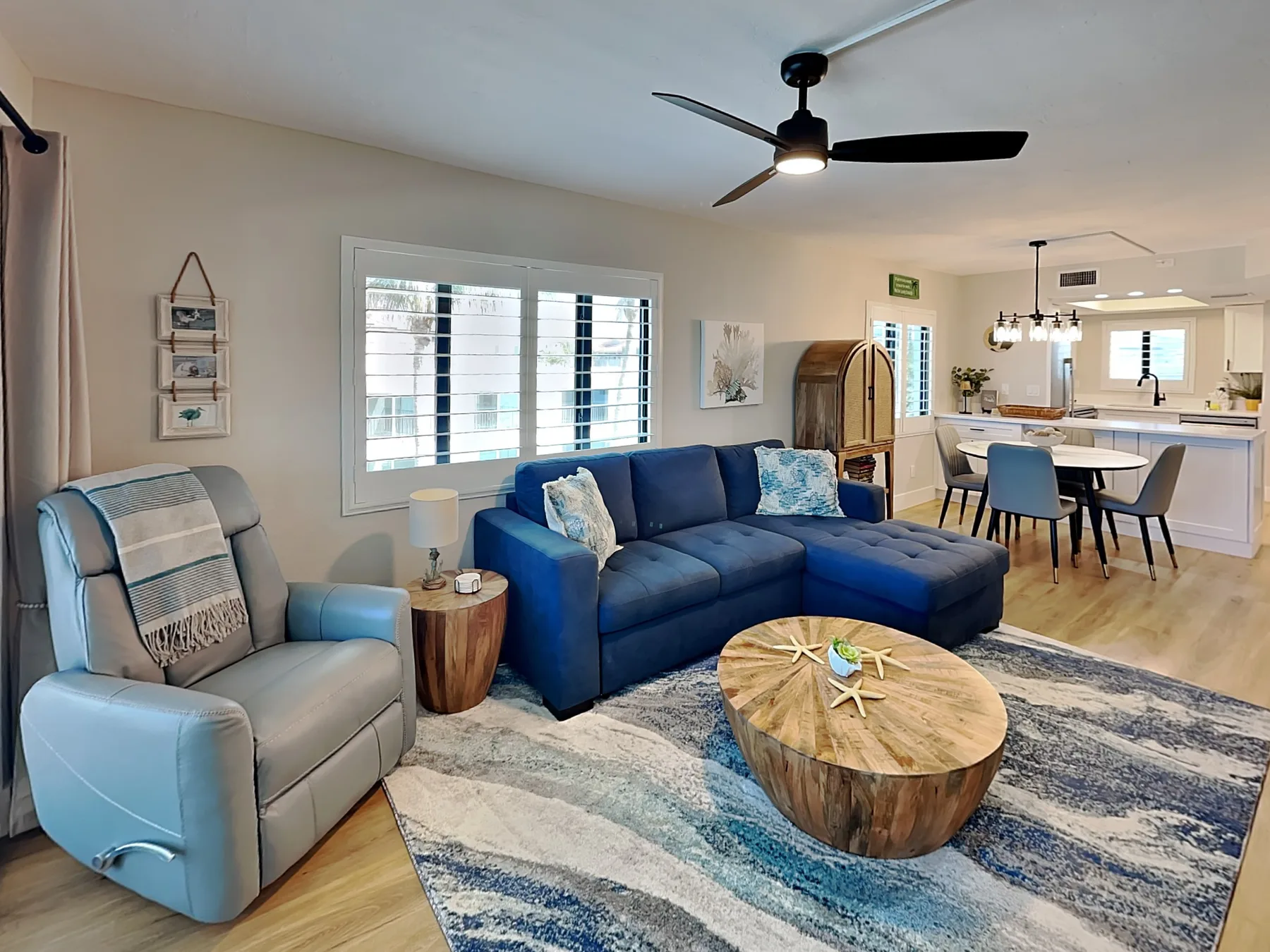 A living room with a blue sectional and a dining area beyond.