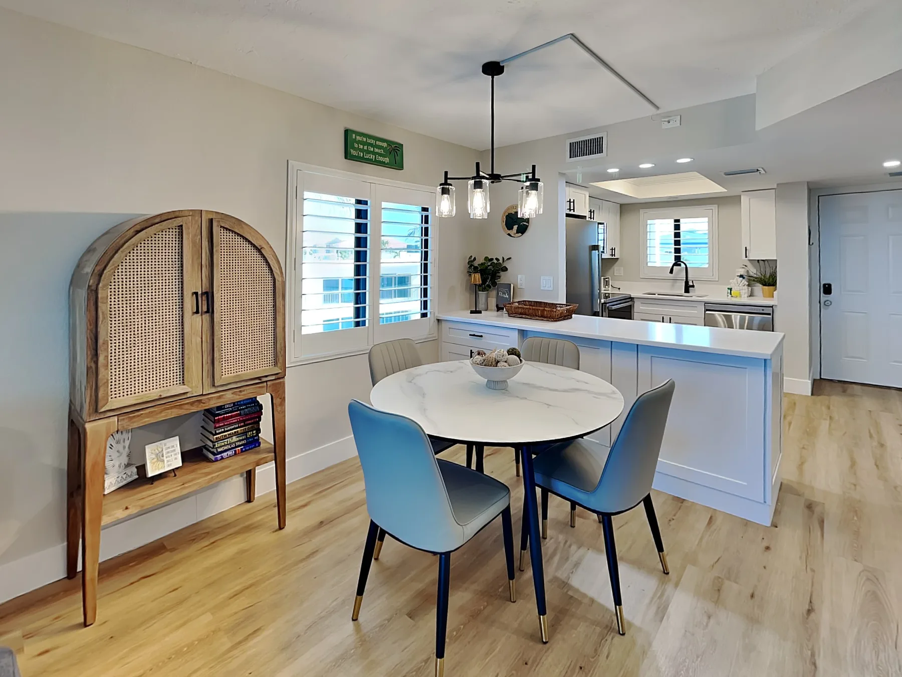 An open-plan dining area and kitchen with a round table and blue seating.
