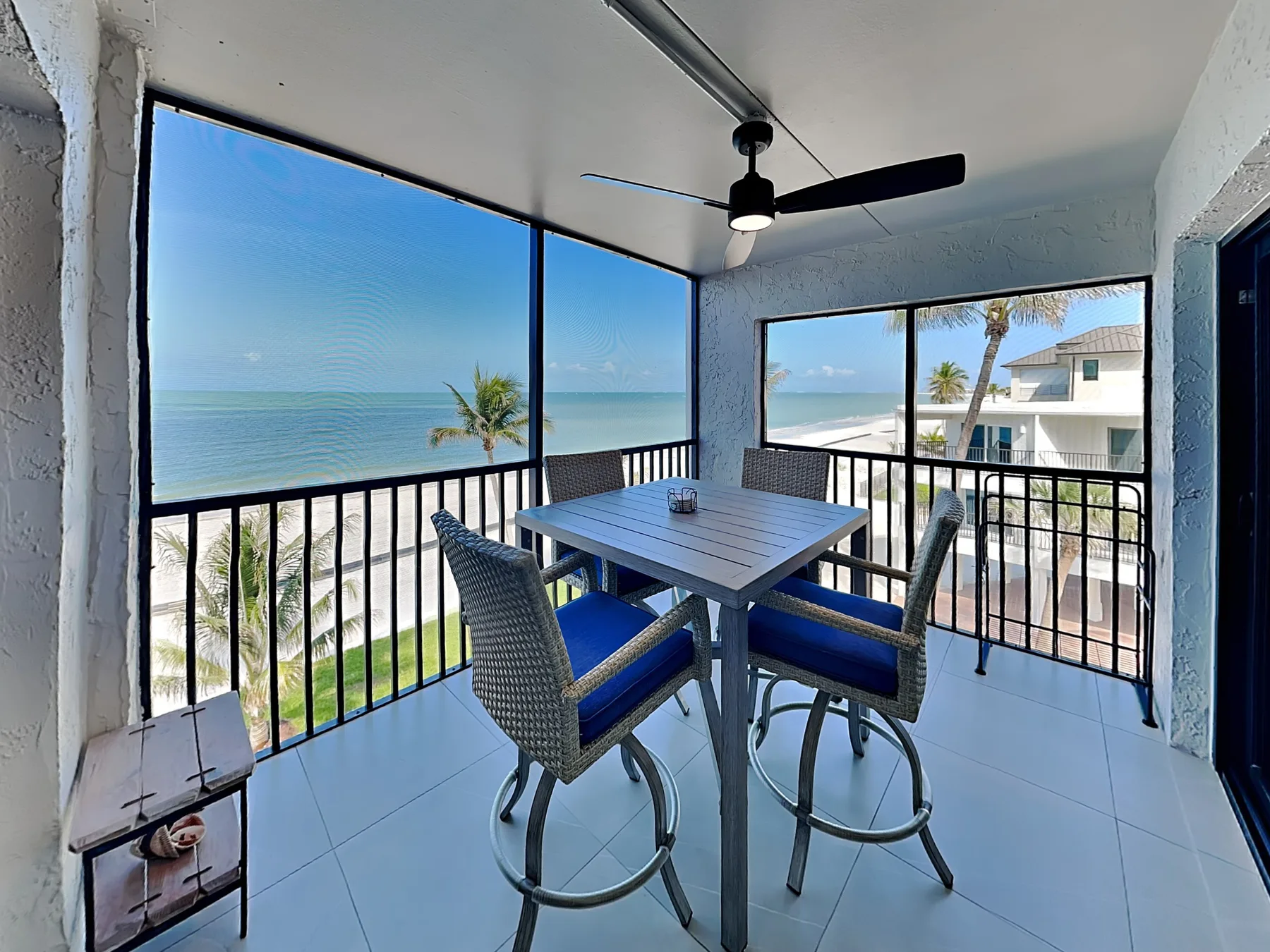 A covered balcony with a table and seating overlooks the ocean.