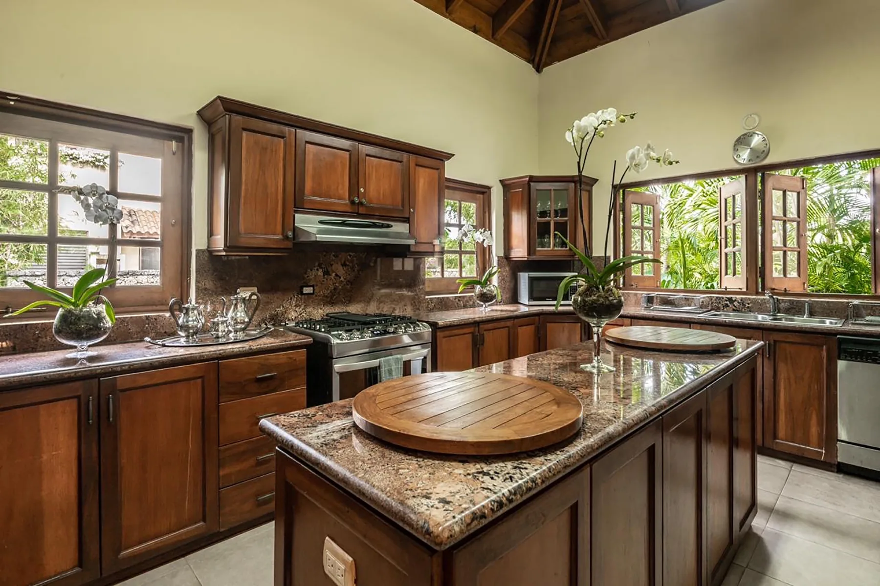 A spacious kitchen with wooden cabinets, stone counters, and a central island.