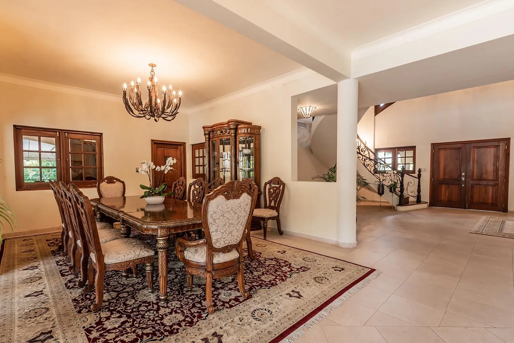 A formal dining room with a long table, chairs, and a chandelier.