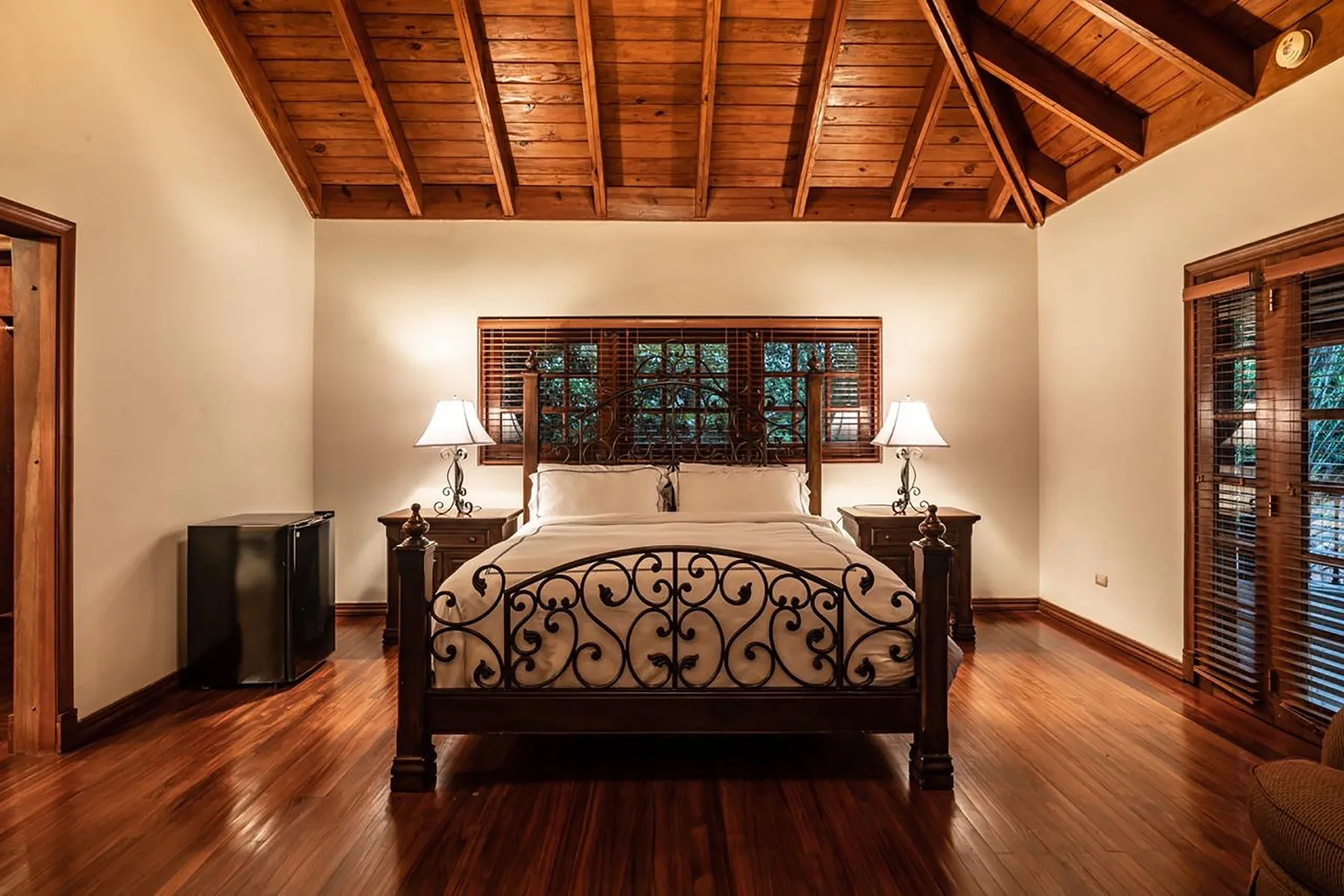 A bedroom with a dark wood bed beneath a sloped wooden ceiling.