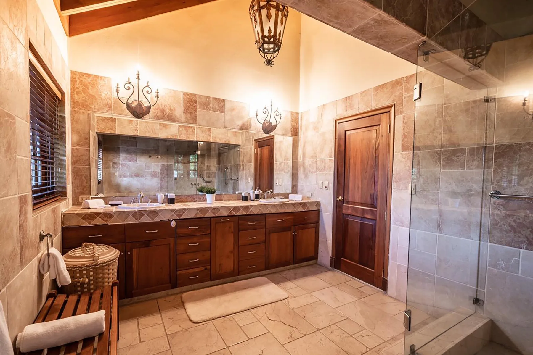 A bathroom with a long vanity, sink, and glass shower area.