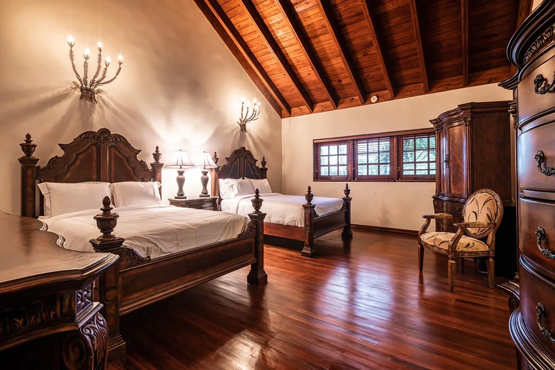 A bedroom with two beds beneath a high wooden ceiling.