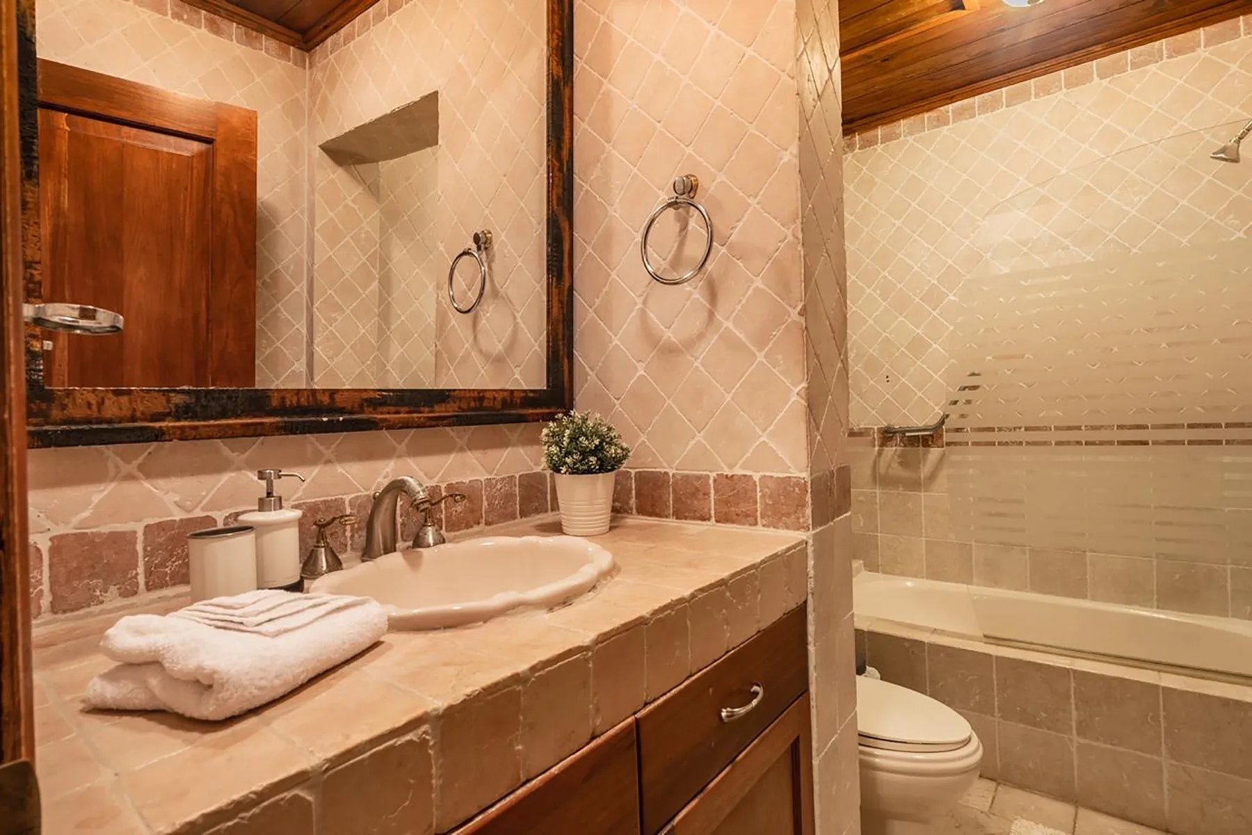 A tiled bathroom with a sink, mirror, and bathtub.