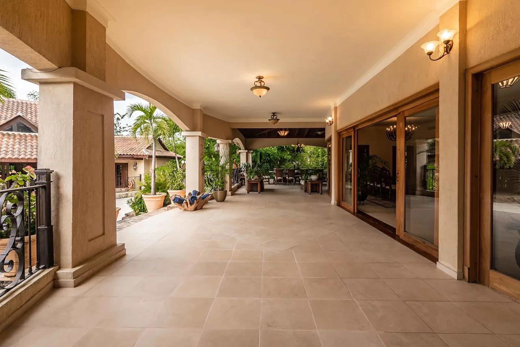 A covered patio with tiled flooring, columns, and sliding glass doors.