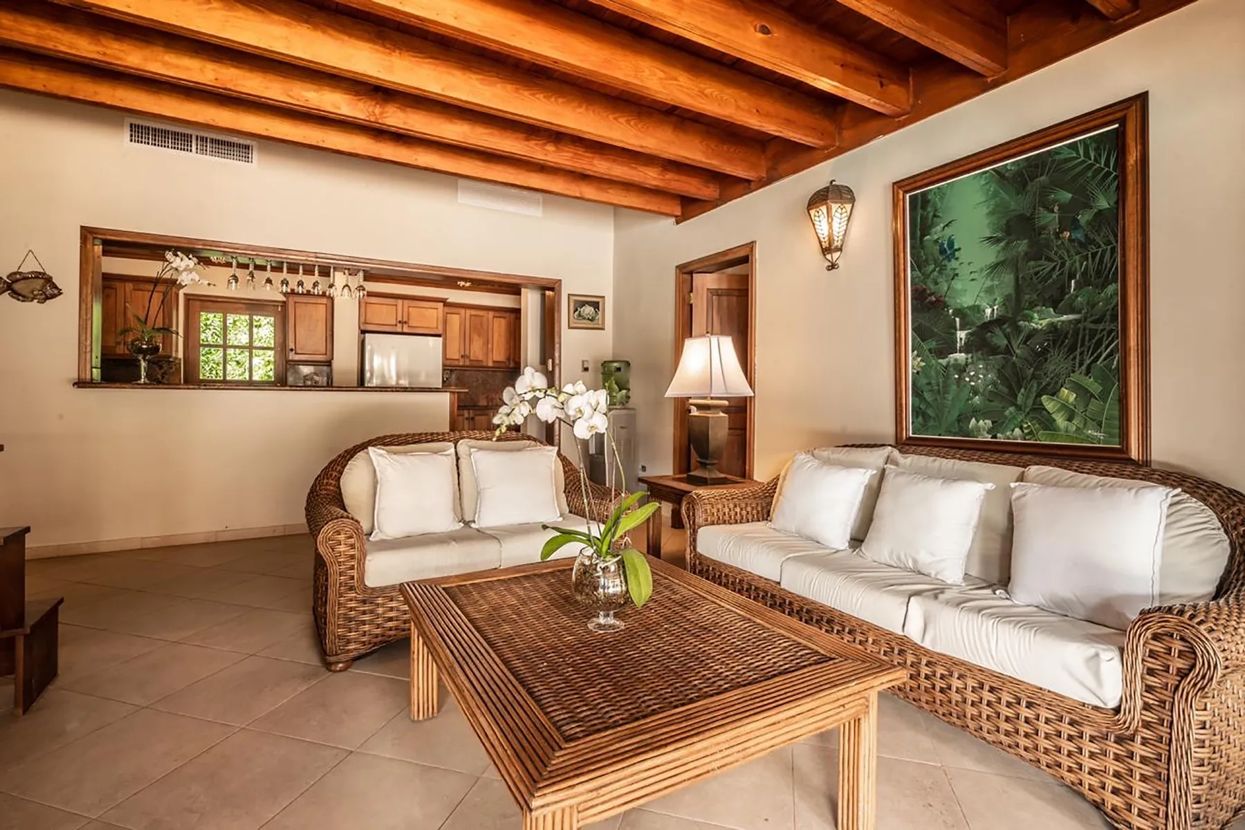 A living room with wicker seating, a wooden coffee table, and exposed ceiling beams.