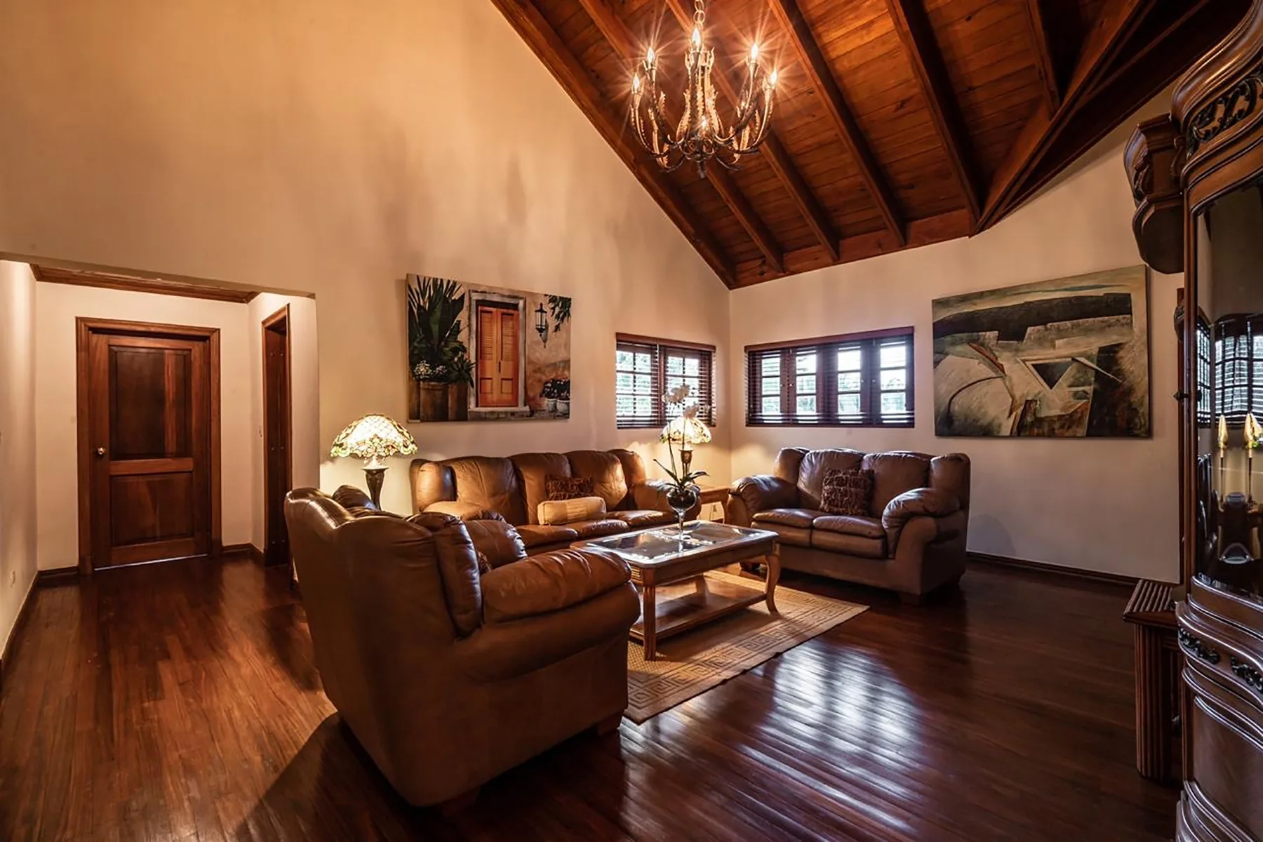 A living room with leather seating, a wooden coffee table, and a high wood ceiling.