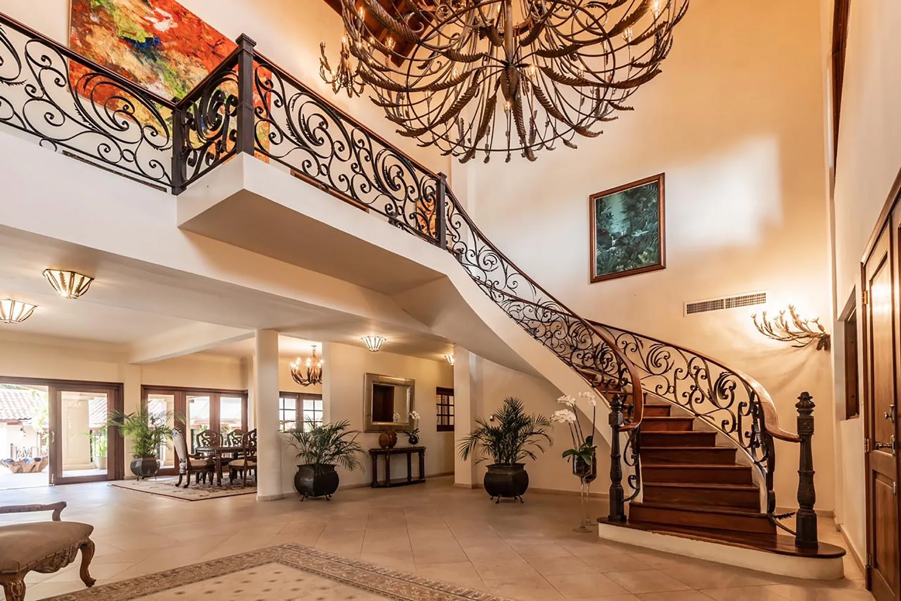 A grand interior foyer features a curved staircase with ornate railings.