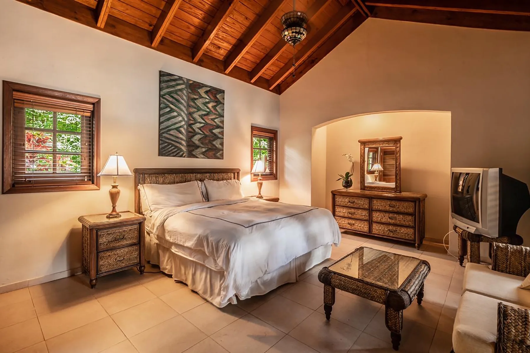 A bedroom with a bed, bedside tables, and a wooden vaulted ceiling.