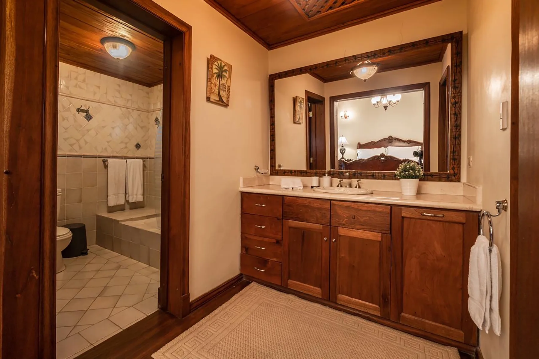 A bathroom vanity with a large mirror stands beside a tiled shower area.