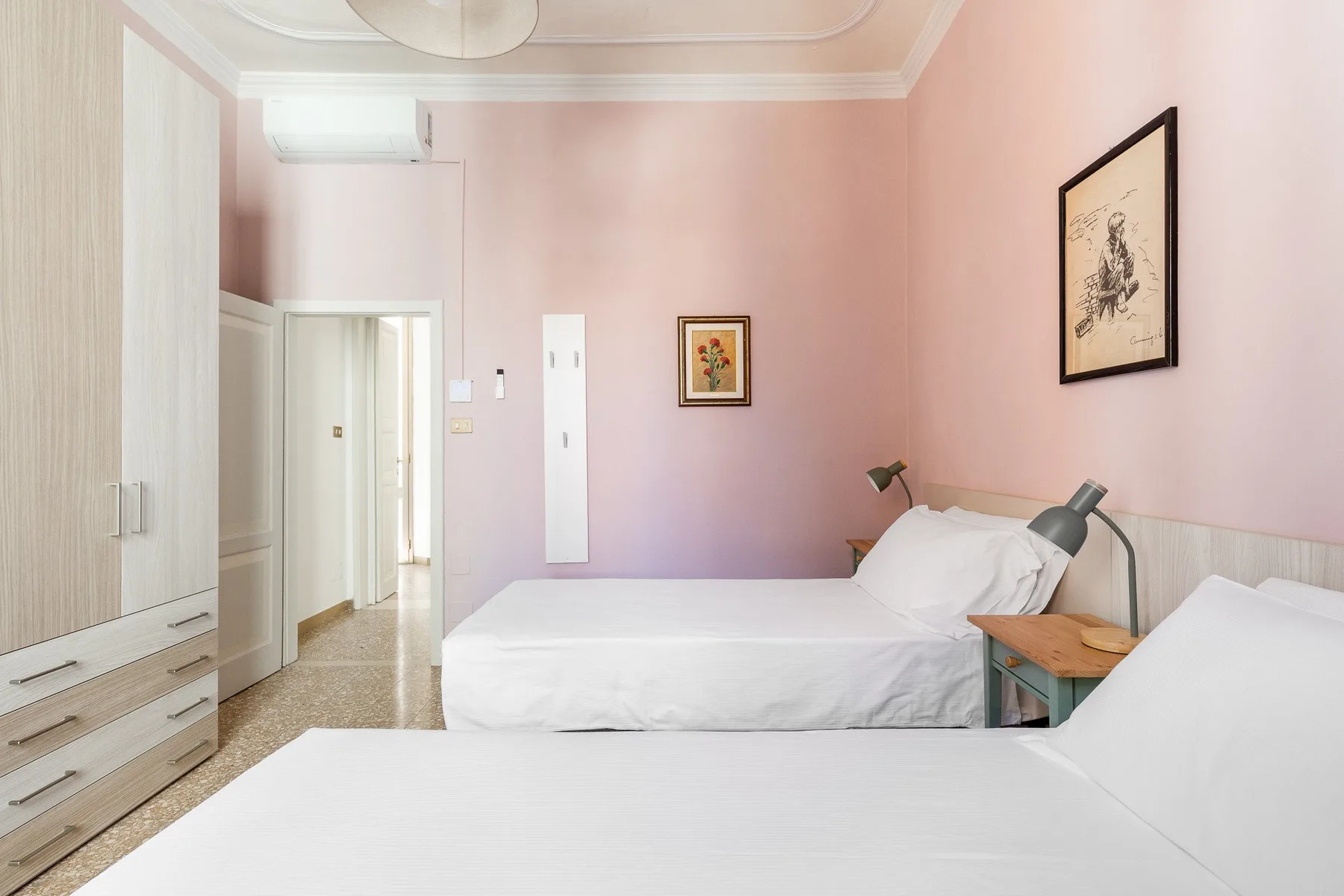 A bedroom with white beds, pink walls, and a wardrobe.