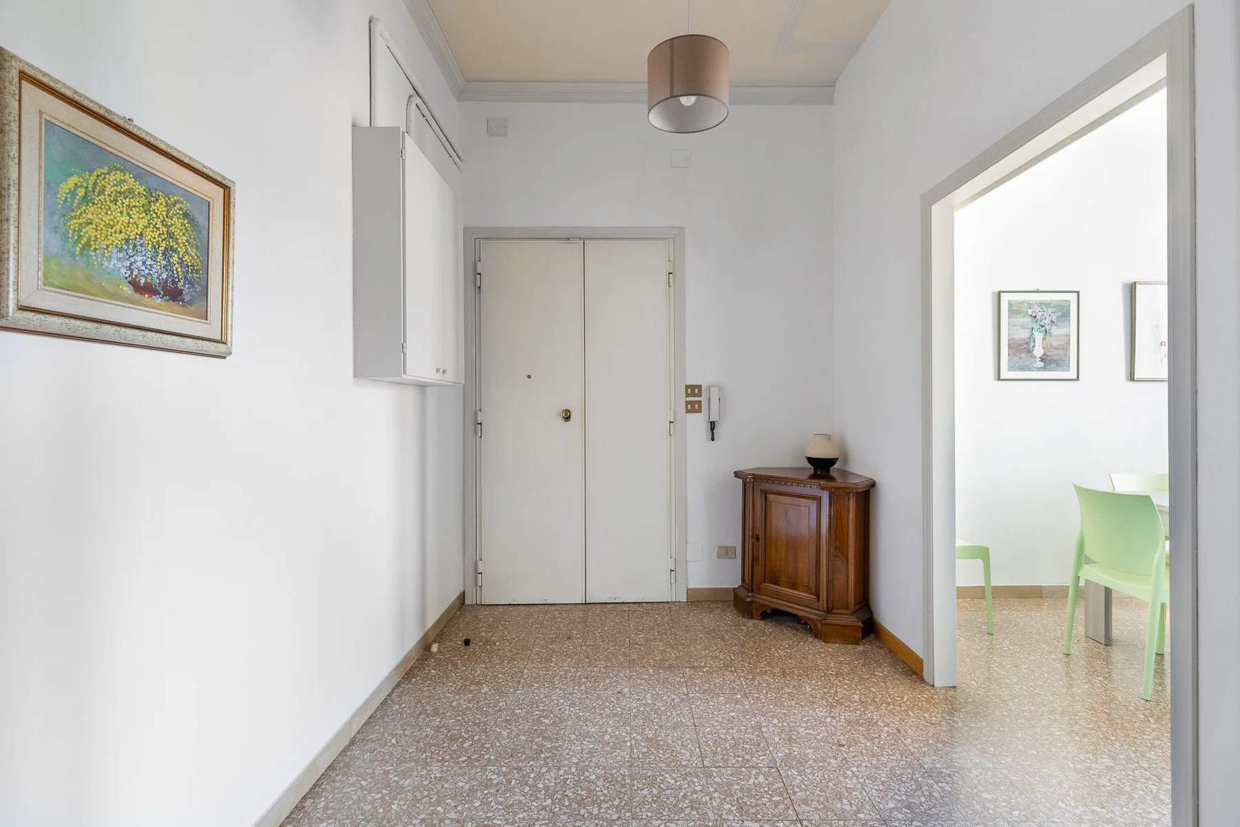 A bright entry hall with a closed door and a small wooden cabinet.