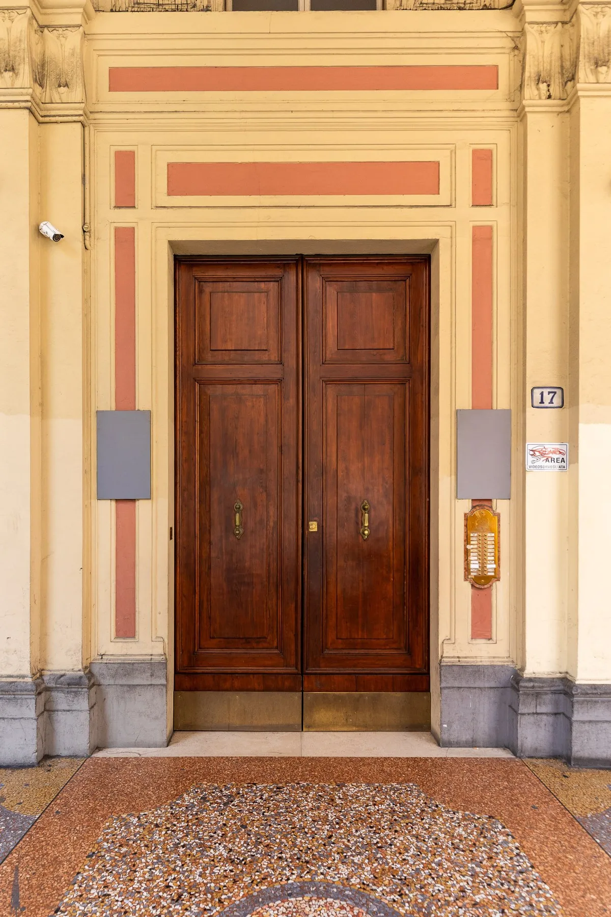 An ornate double wooden entrance door is set within a decorated stone facade.