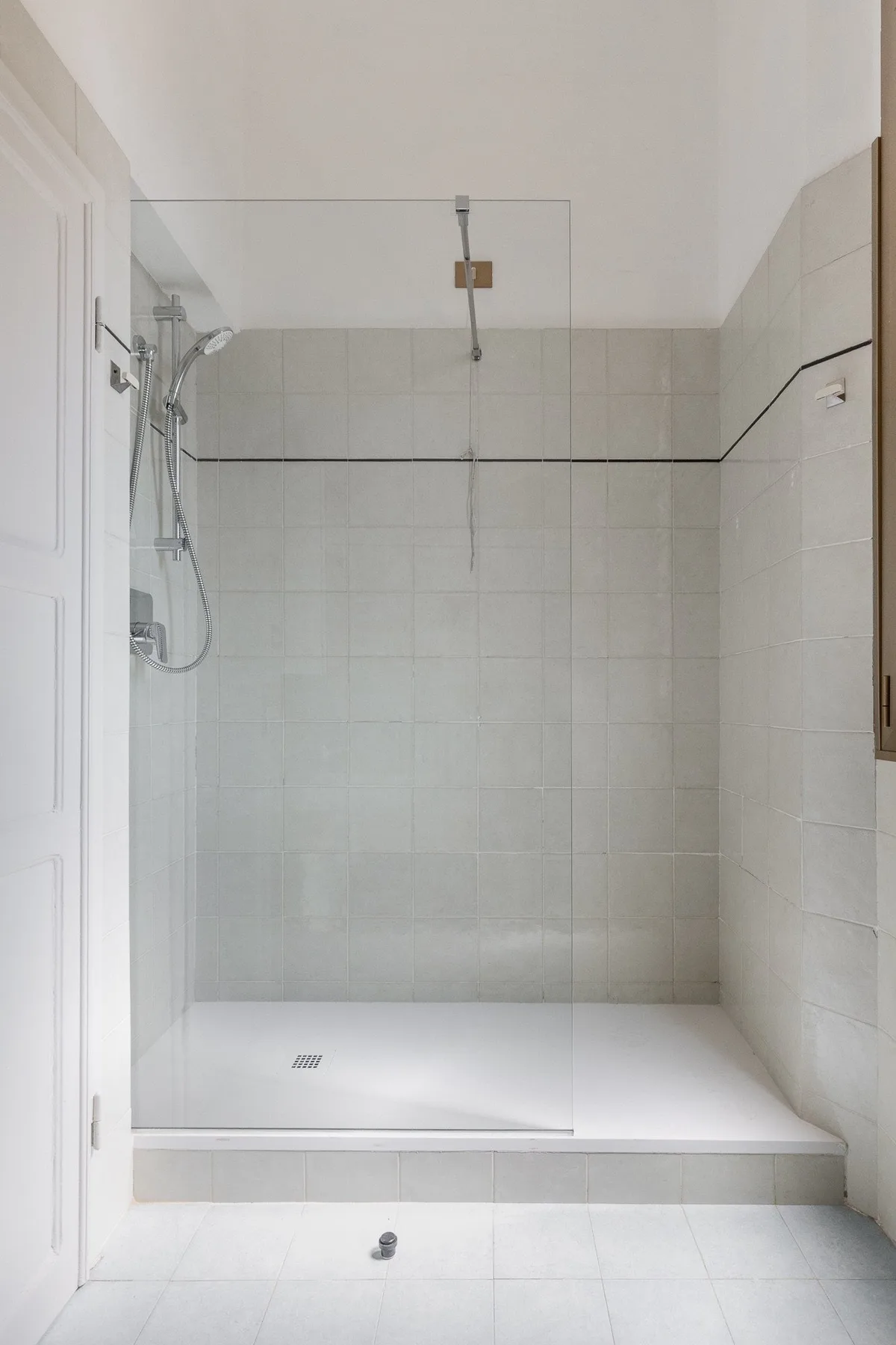 A tiled bathroom with a glass-screened shower and white floor.