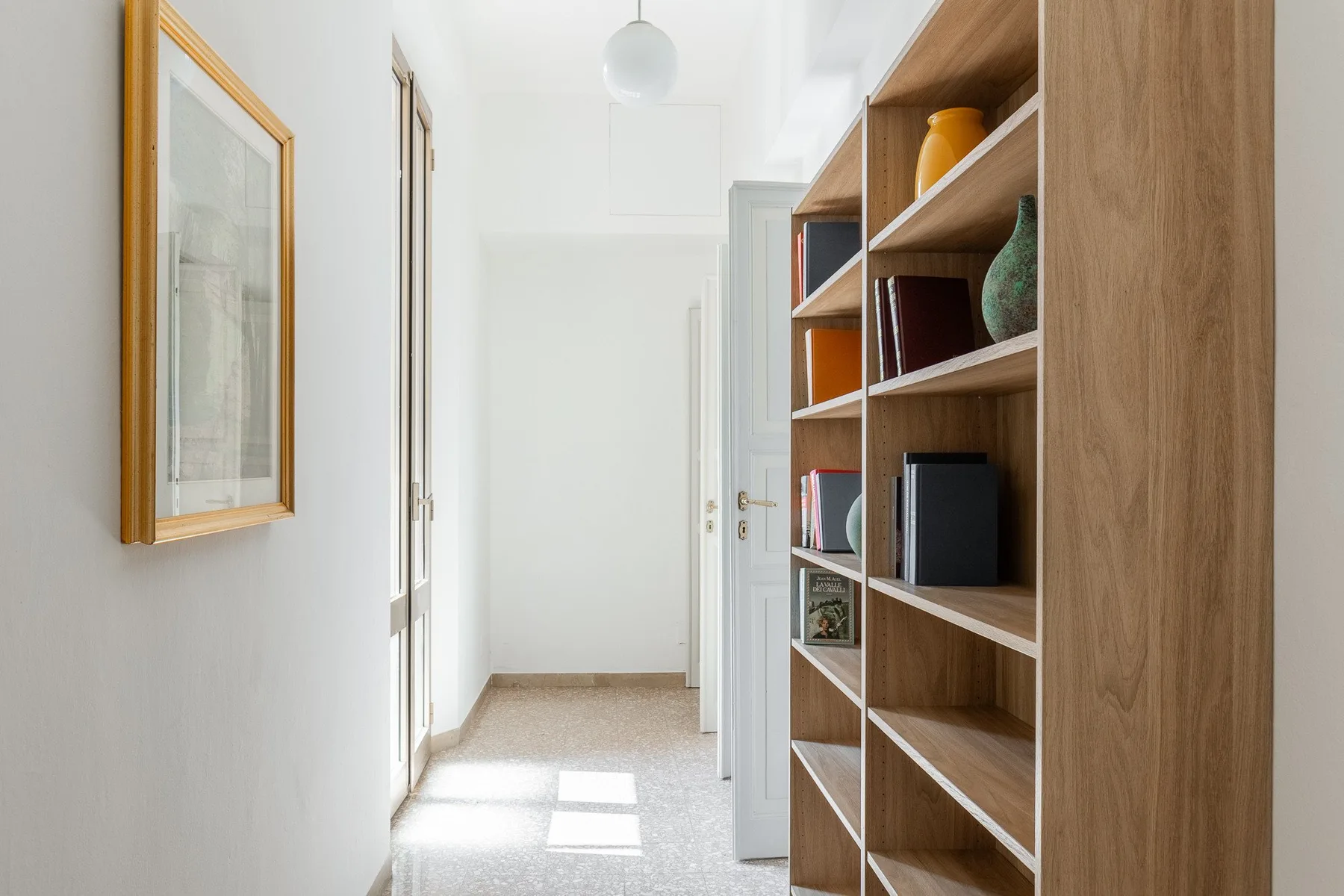A bright hallway with built-in wooden shelving along one wall.