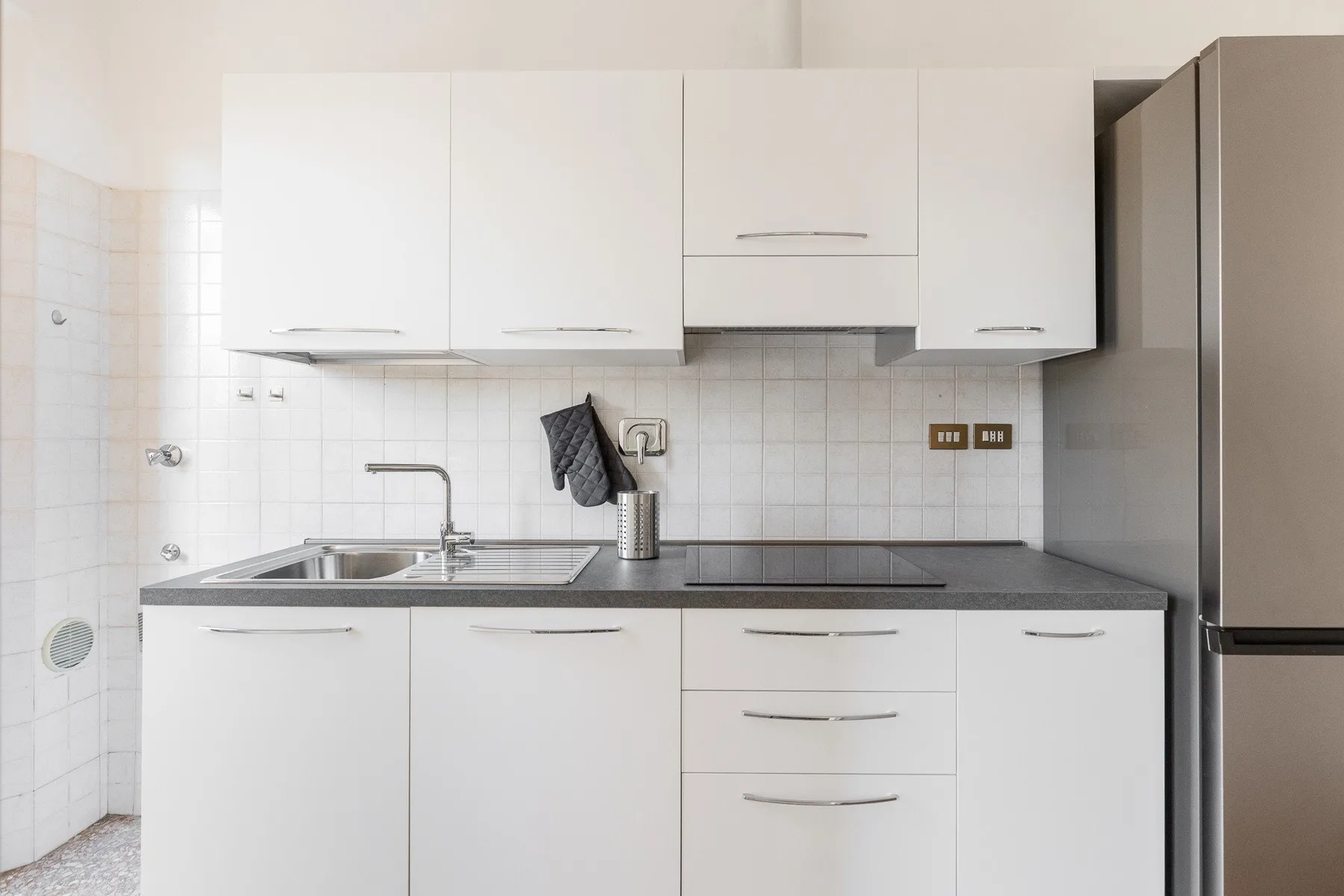 A bright kitchen with white cabinets, a countertop, and a sink.