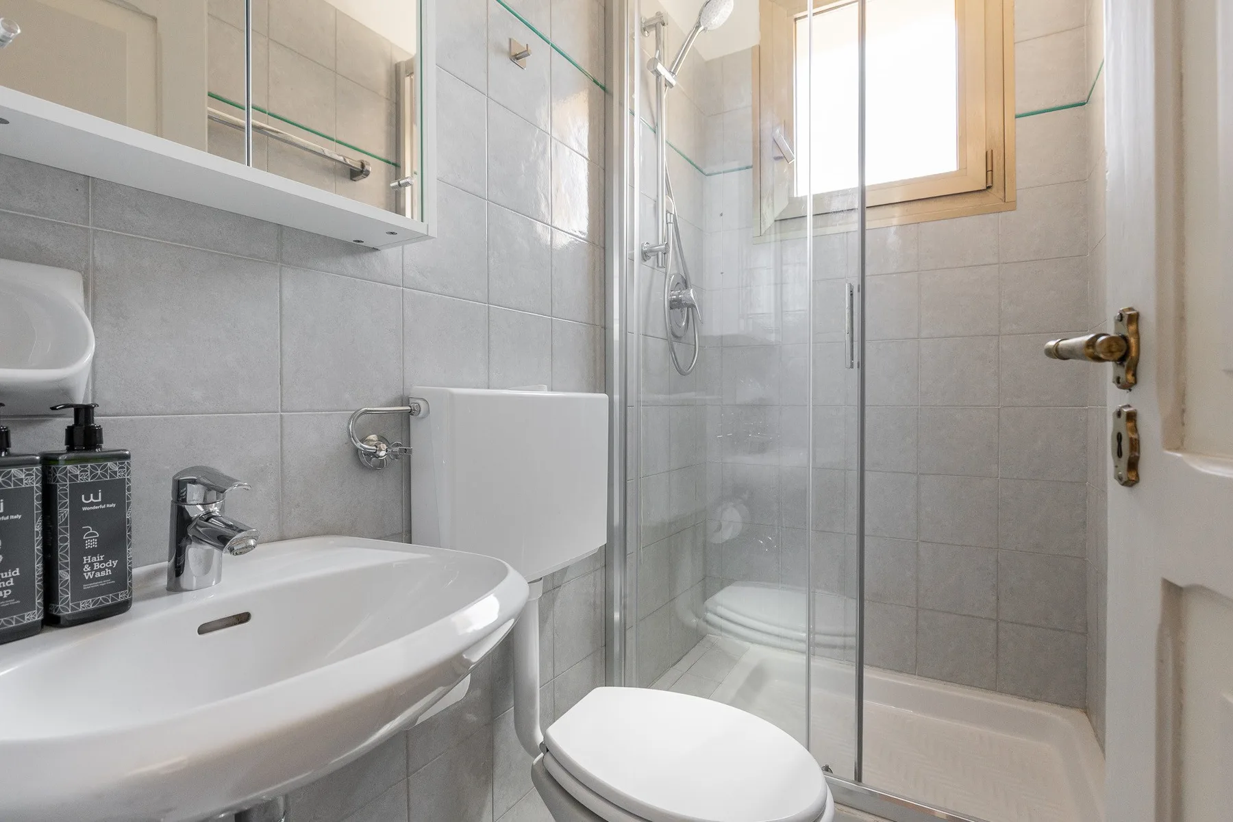 A tiled bathroom with a sink, toilet, and glass shower.