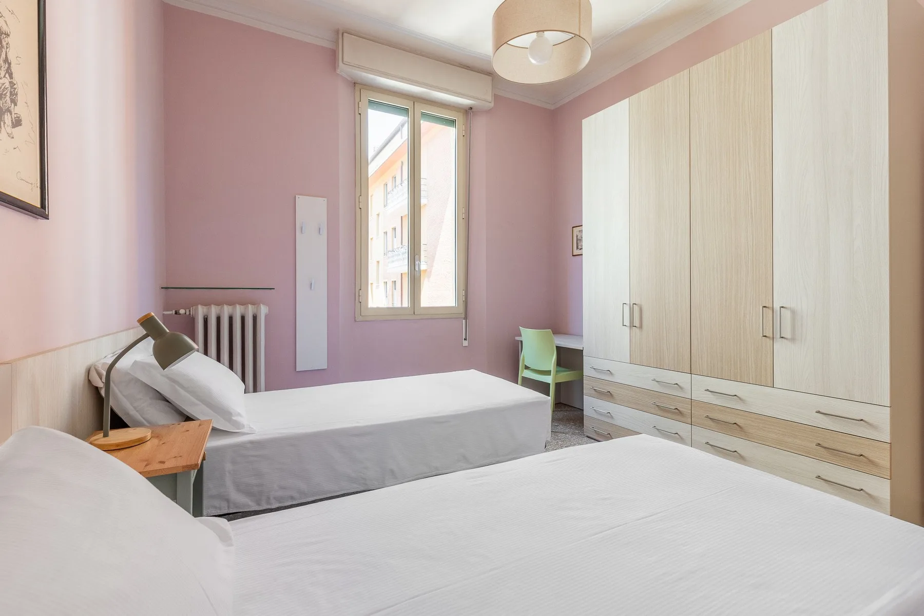 A pink bedroom with two beds and a large wardrobe.