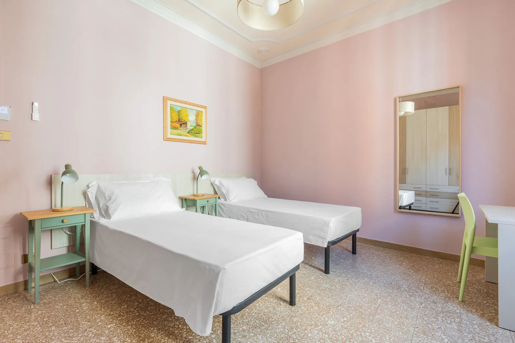 A twin bedroom with two beds, bedside tables, and a framed picture on the wall.