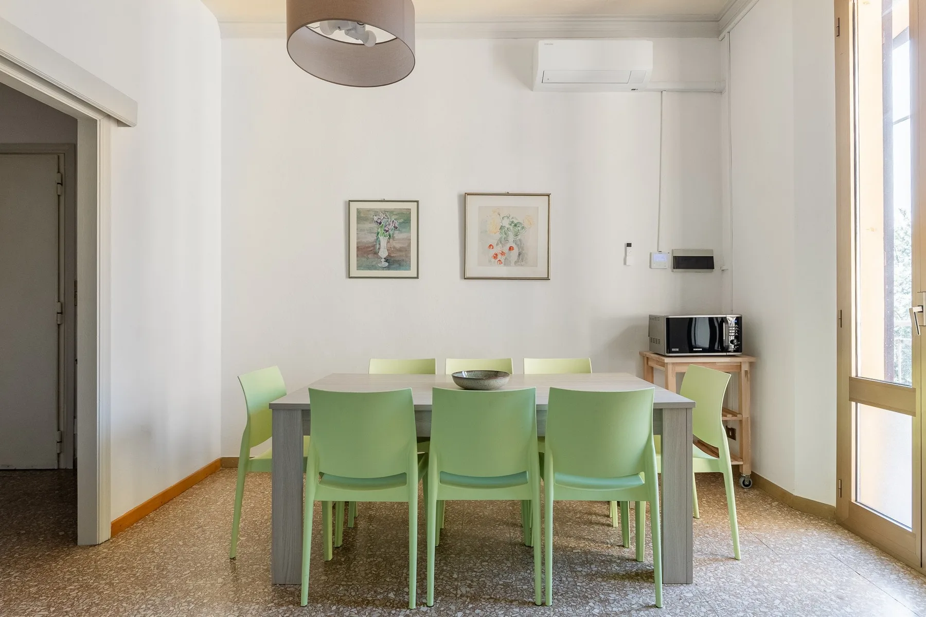 A dining area with a table, green seating, and framed artwork on the wall.