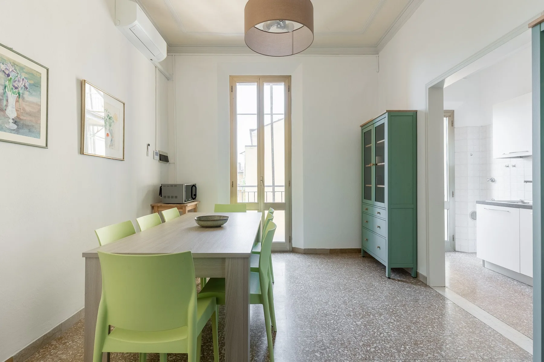 A bright dining area with a table and green seating beside a kitchen.