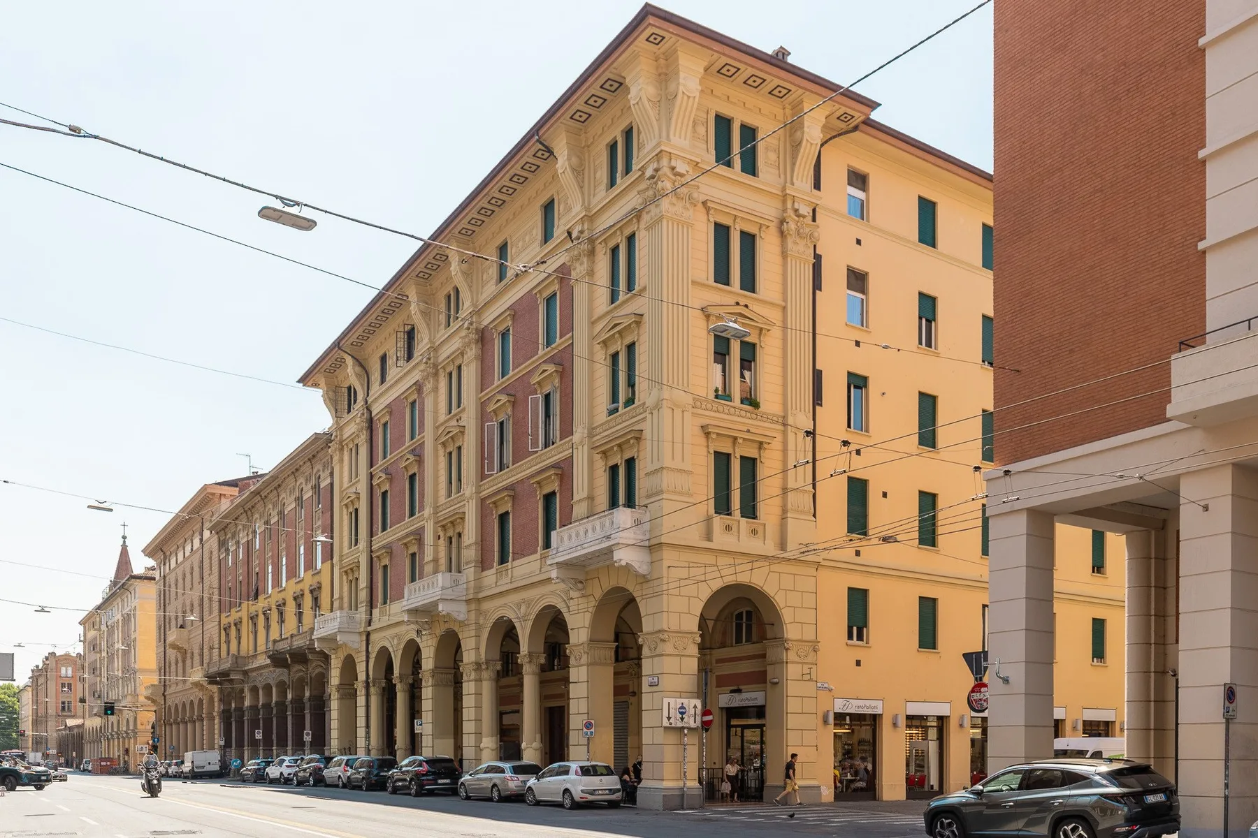 A city street lined with multistory buildings and arcaded ground floors.