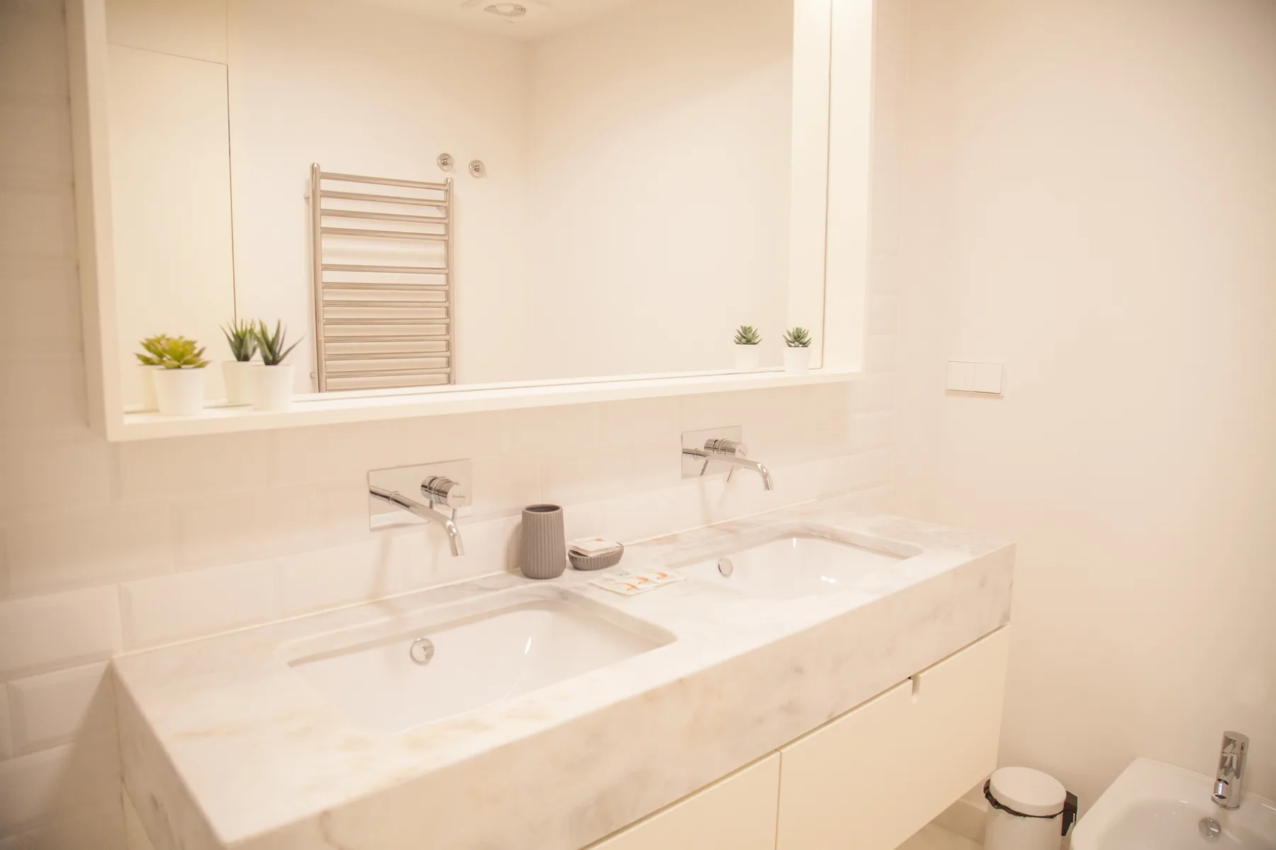 Un tocador de baño con dos lavabos está bajo un gran espejo.