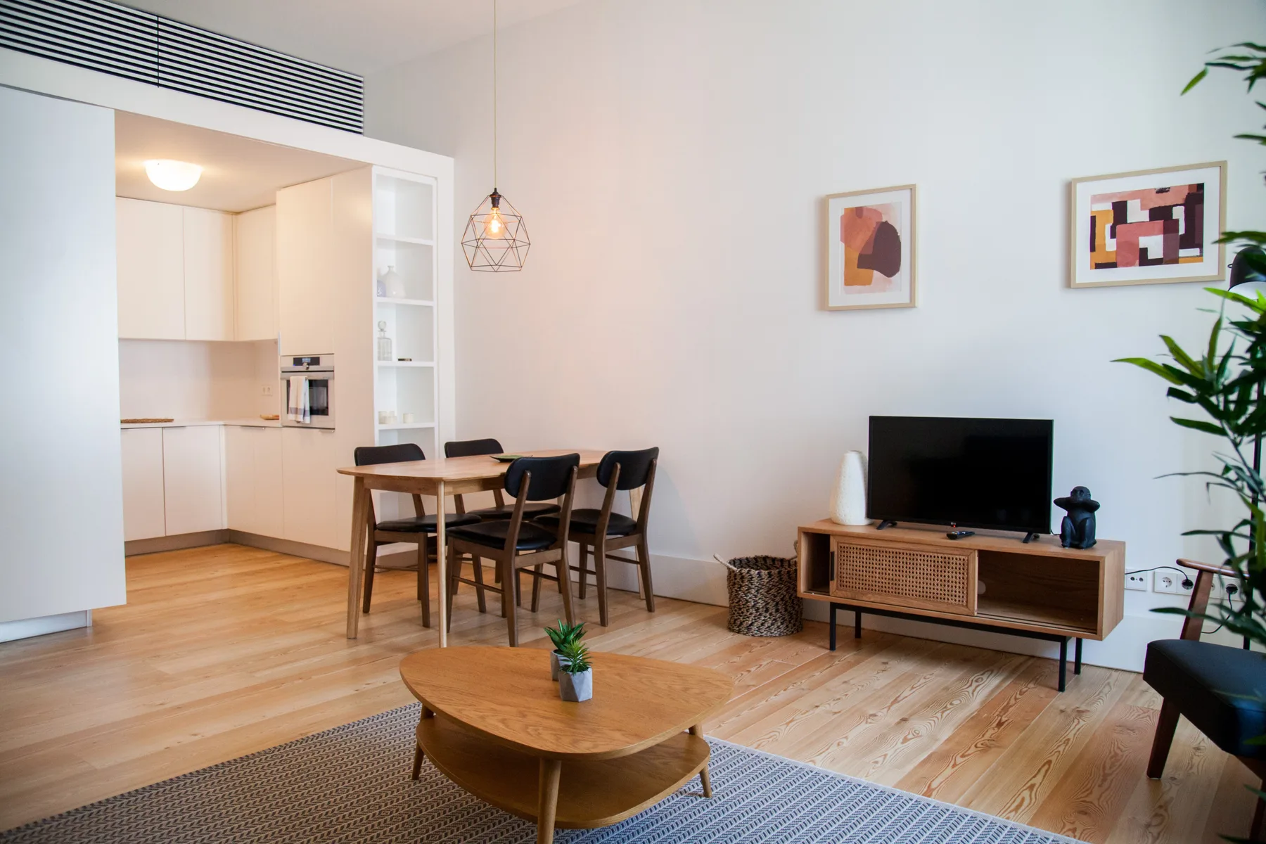 Sala de estar y comedor con televisión y cocina abierta.