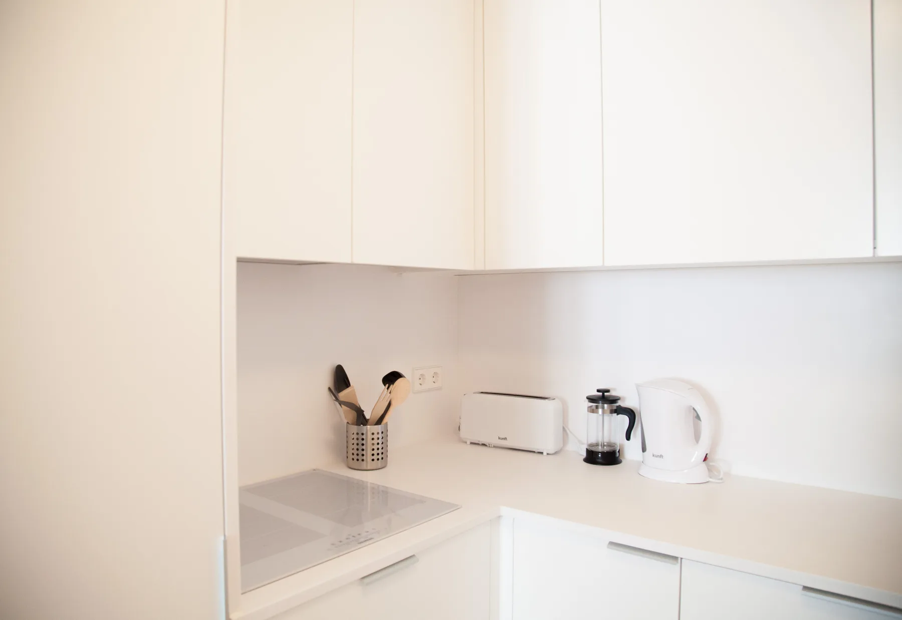Una cocina pequeña con placa de cocción, tostadora, cafetera y hervidor.